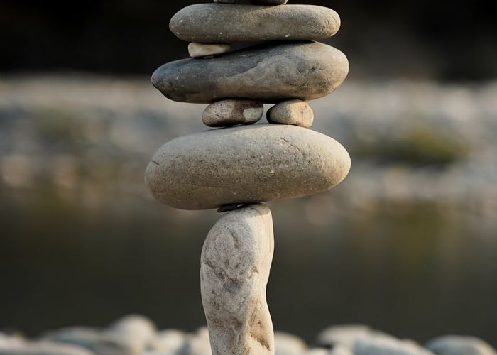 Minimalist stack of stones near a calm mint-colored river
